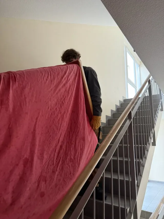Sorgfältig verpacktes Möbelstück wird die Treppe hinuntergetragen
