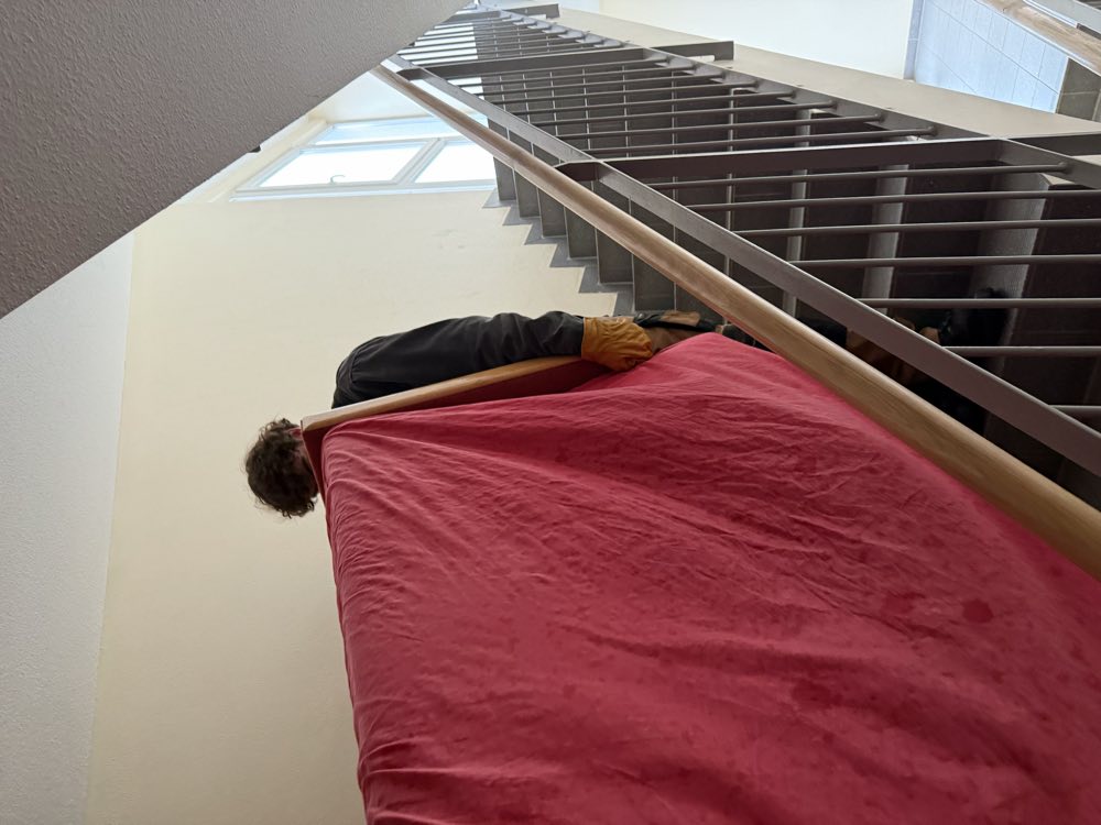 Sorgfältig verpacktes Möbelstück wird die Treppe hinuntergetragen